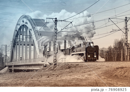 Steam retro train moves on the bridge from the station. 76908925