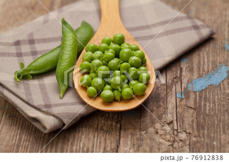 Fresh green peas in wooden spoon on white vintage background. Healthy eating 76912838