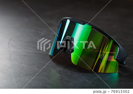 Green sports glasses with a mirror lens on a dark background Green sports glasses with a mirror lens on a dark background 76913302