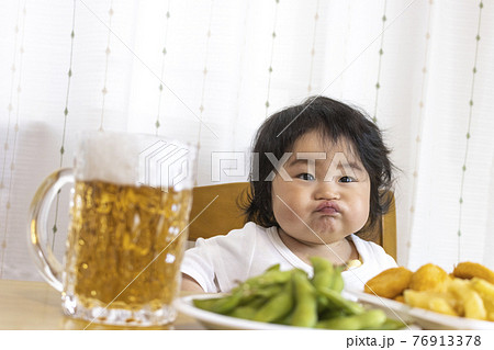 家のテーブルでビールを飲む赤ちゃんのイメージ(0歳、生後9か月、日本人、女の子) 家のテーブルでビールを飲む赤ちゃんのイメージ(0歳、生後9か月、日本人、女の子) 76913378