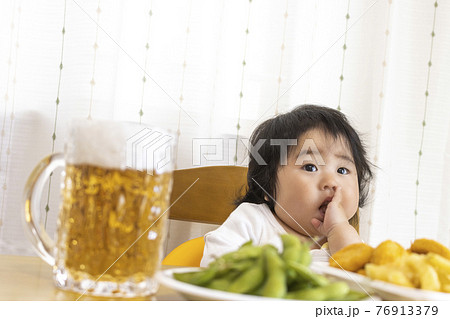 家のテーブルでビールを飲む赤ちゃんのイメージ(0歳、生後9か月、日本人、女の子) 家のテーブルでビールを飲む赤ちゃんのイメージ(0歳、生後9か月、日本人、女の子) 76913379