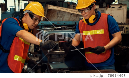 Group of skillful factory workers using machine equipment in workshop 76914493