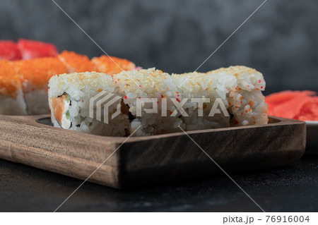 Sushi set isolated on a wooden board on black background Sushi set isolated on a wooden board on black background 76916004