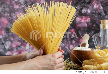 Woman hands holding spaghetti on colorful background with oil and flour Woman hands holding spaghetti on colorful background with oil and flour 76916064