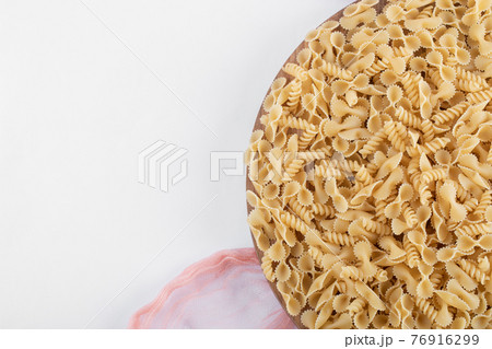 Bunch of various pasta on wooden plate with pink cloth Bunch of various pasta on wooden plate with pink cloth 76916299