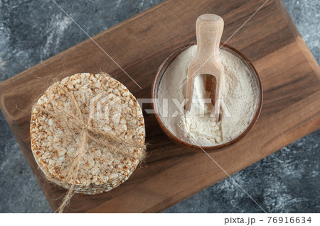Stack of rice cakes and bowl of flour on wooden board 76916634