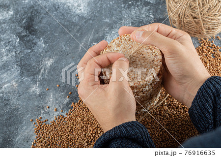 Female hands gripping delicious crispbread on marble background 76916635