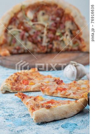 Margarita pizza slices on blue table served with sauces 76916636