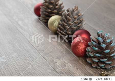 Natural oak tree cones on a wooden deck with glittering ornaments around 76916641