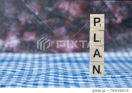 Plan writing with black letters on wooden dices on blue checked towel Plan writing with black letters on wooden dices on blue checked towel 76916814