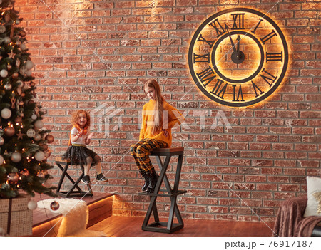 little cute sisters waiting for the beginning of the holiday in a cozy living room . little cute sisters waiting for the beginning of the holiday in a cozy living room . 76917187