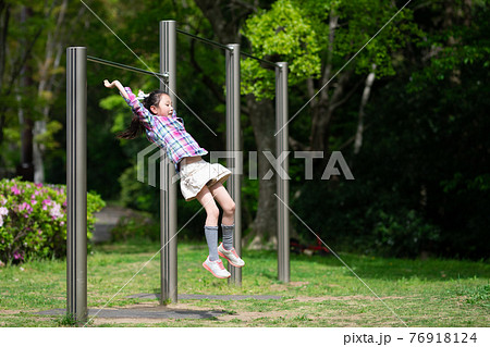 鉄棒で遊ぶ女の子 76918124