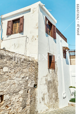 Narrow street with houses whitewashed walls and wooden shutters on windows Narrow street with houses whitewashed walls and wooden shutters on windows 76919499