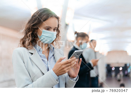 young woman with smartphone while waiting for a subway train. 76920347