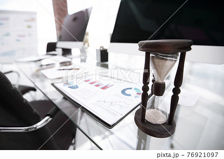 financial graph and the hourglass on the Desk 76921097