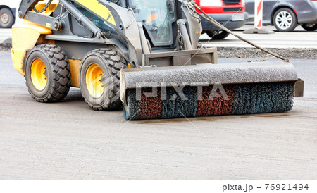 A small grader with a trailed nylon brush with hydraulics cleans the repaired section of the road from dirt. 76921494