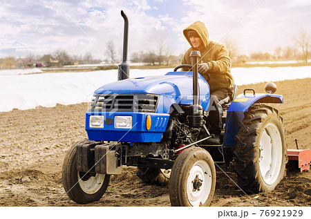 Farmer on a tractor with milling machine loosens, grinds and mixes soil. Loosening the surface, cultivating the land for further planting. Farming and agriculture. Cultivates the soil. Plows a field. Farmer on a tractor with milling machine loosens, grinds and mixes soil. Loosening the surface, cultivating the land for further planting. Farming and agriculture. Cultivates the soil. Plows a field. 76921929
