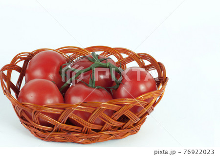 branch of ripe tomatoes in a wicker basket.isolated on white 76922023