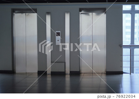 closed Elevator doors and control panel in a modern office building 76922034