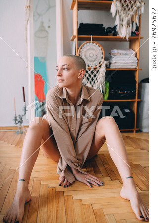 Girl with short hair and tattoos sitting at the floor and posing to the camera 76925672