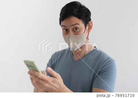 Man with mask is happy with the promotion in the smartphone application. 76931710