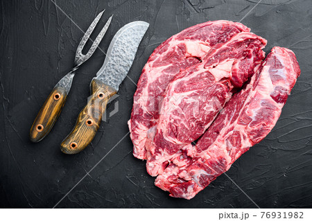 Raw marbled meat , Rib eye cut, on black stone background, top view flat lay Raw marbled meat , Rib eye cut, on black stone background, top view flat lay 76931982