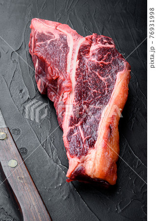 Classic fresh beef striploin steaks,T bone cut, on black stone background 76931998