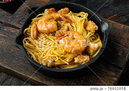 Traditional Italian dish. pasta with pesto ricotta parmesan and grilled seafood , in cast iron frying pan, on old dark wooden table 76932058