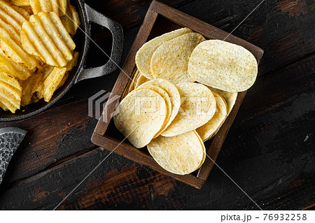 Crispy potato chips, on old dark wooden table , top view flat lay Crispy potato chips, on old dark wooden table , top view flat lay 76932258