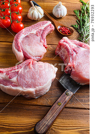 Raw pork meat chopes with herbs and spices with meat american cleaver on wooden background side view vertical 76932293