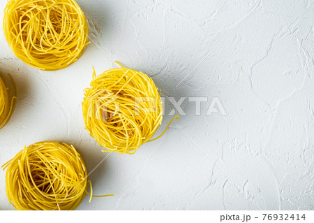 Unooked Italian Tagliolini paglia pasta, on white stone surface, top view flat lay, with copy space for text Unooked Italian Tagliolini paglia pasta, on white stone surface, top view flat lay, with copy space for text 76932414
