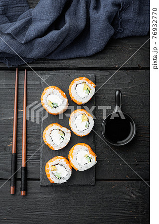 Sushi roll, Philadelphia with salmon, smoked eel, avocado, cream cheese, on black wooden table background, top view flat lay Sushi roll, Philadelphia with salmon, smoked eel, avocado, cream cheese, on black wooden table background, top view flat lay 76932770