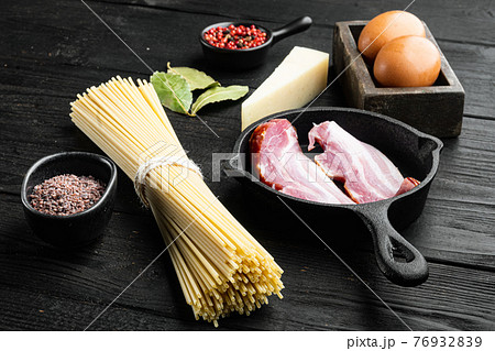 Traidtional Italian Pasta Carbonara Ingredients. Bacon, Spaghetti, Parmesan and pecorino cheese, egg, garlic, on black wooden background 76932839