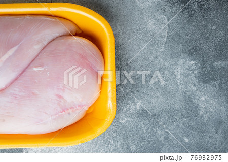 Raw chicken breast fillet in tray, on gray background with copy space for text 76932975