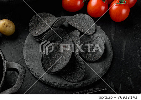 Cheese and chive potato crisp snack, on black stone background Cheese and chive potato crisp snack, on black stone background 76933143