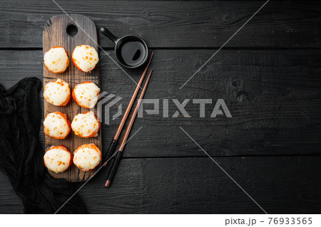 Baked sushi maki rolls with salmon, crab, cucumber, avocado, flying fish roe and spicy sauce, on black wooden table background, top view flat lay , with copyspace and space for text Baked sushi maki rolls with salmon, crab, cucumber, avocado, flying fish roe and spicy sauce, on black wooden table background, top view flat lay , with copyspace and space for text 76933565