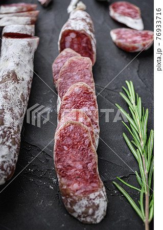 Dry cured fuet salami sausage slices on balck background Dry cured fuet salami sausage slices on balck background 76933716