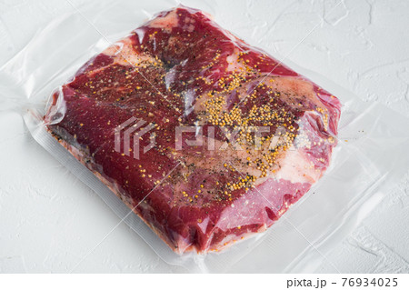 Beef navel, raw beef brisket meat,with ingredients for smoking making barbecue, pastrami, cure, vacuum sealed ready for sous vide cooking, on white stone background 76934025