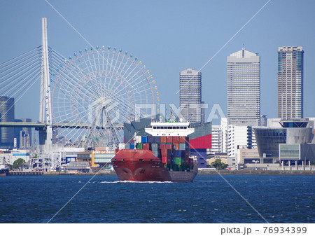 大阪港を白波を立てて出港する赤いコンテナ船 76934399