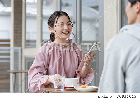 カフェで談笑する若いカップル カフェで談笑する若いカップル 76935015