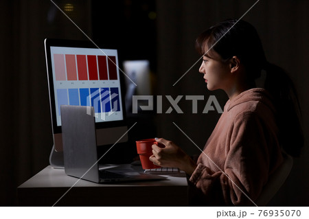 深夜に自宅で仕事をする若い女性の写真素材