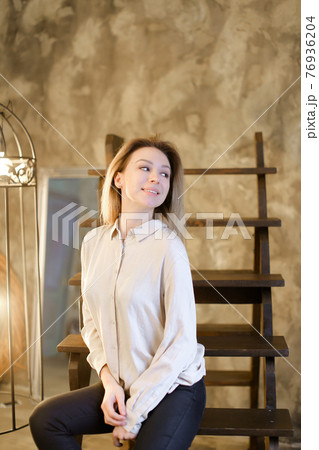Portrait of young blonde girl sitting on wooden stairs. 76936204