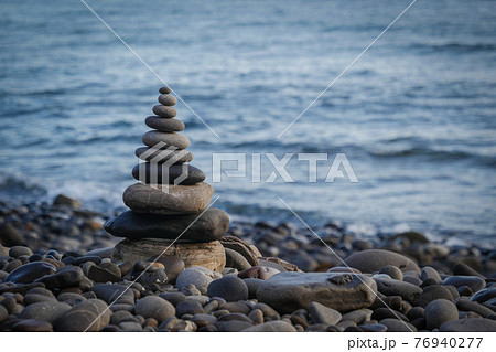 Stone piles made along a beach and the sea in the background 76940277