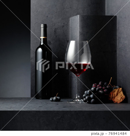 Red wine and blue grapes on a black stone table. Red wine and blue grapes on a black stone table. 76941484