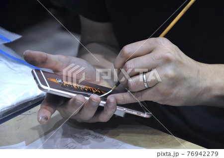 KUALA LUMPUR, MALAYSIA -FEBRUARY 22, 2017: Man's hand is painting on the back of the phone KUALA LUMPUR, MALAYSIA -FEBRUARY 22, 2017: Man's hand is painting on the back of the phone 76942279
