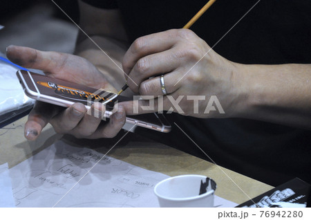 KUALA LUMPUR, MALAYSIA -FEBRUARY 22, 2017: Man's hand is painting on the back of the phone KUALA LUMPUR, MALAYSIA -FEBRUARY 22, 2017: Man's hand is painting on the back of the phone 76942280