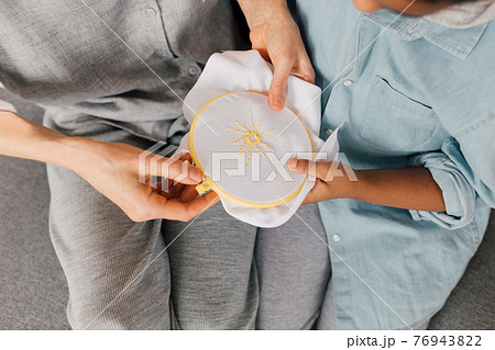 Boy looking at the embroidery while his grandmother sitting at the sofa Boy looking at the embroidery while his grandmother sitting at the sofa 76943822