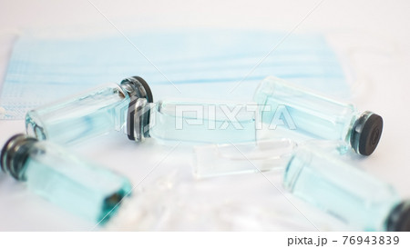 Vial vaccine, top view of glass ampoules with transparent and blue liquid lying on white background, global vaccination concept Vial vaccine, top view of glass ampoules with transparent and blue liquid lying on white background, global vaccination concept 76943839