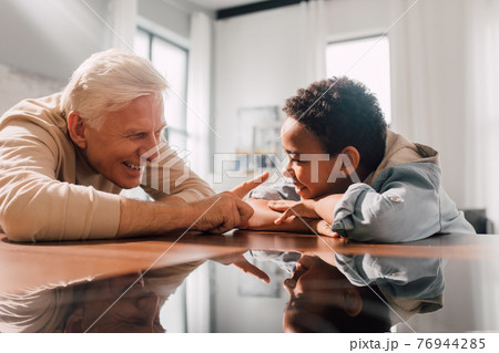 Man touching the nose of his multiracial son with tenderness while sitting 76944285