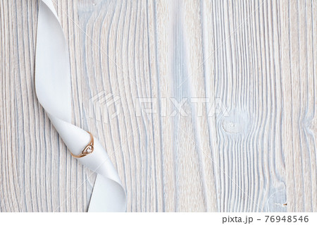 Wedding ring with a white ribbon on a wooden background. Top view. Wedding ring with a white ribbon on a wooden background. Top view. 76948546